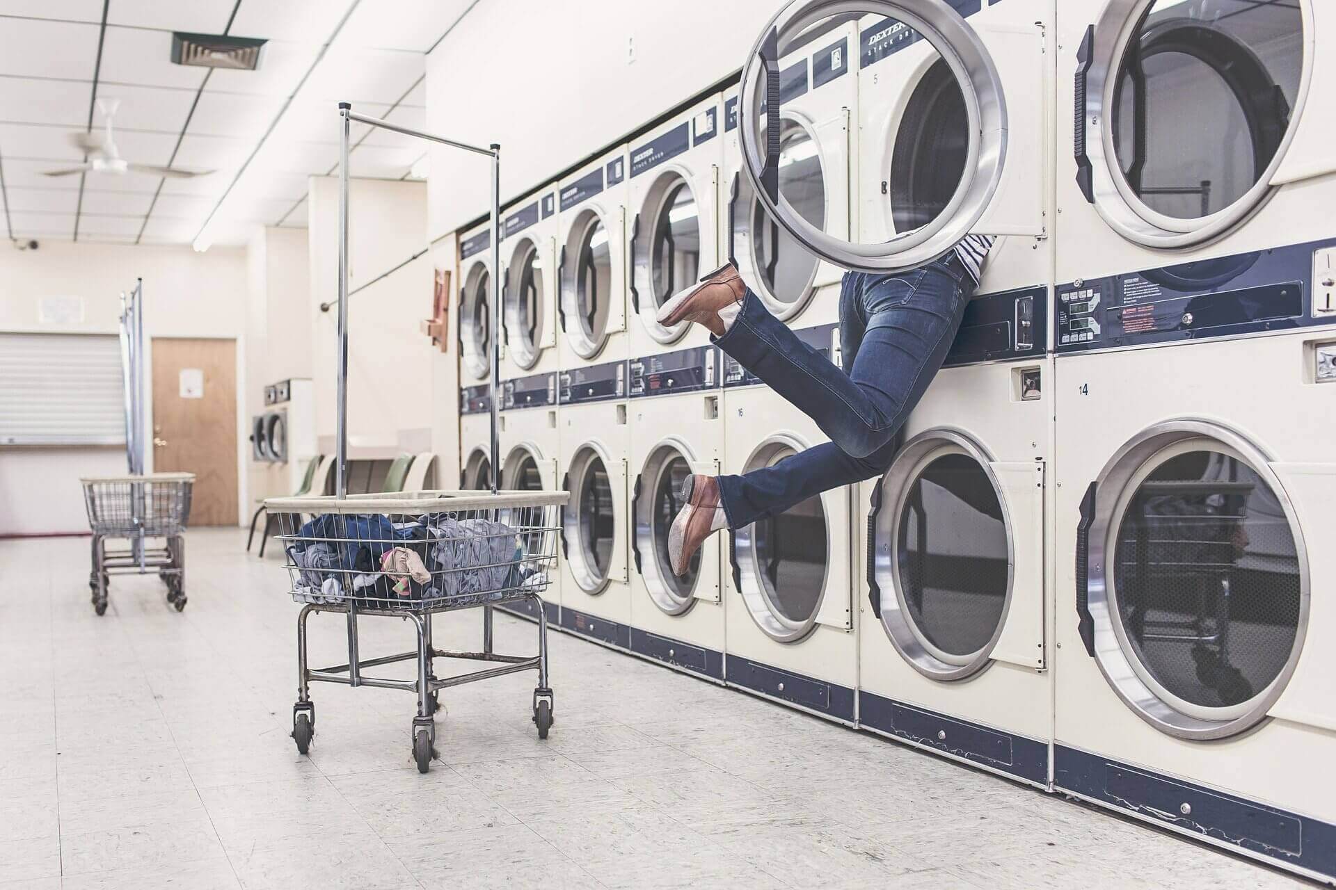 homme mettant la tête dans un lave linge